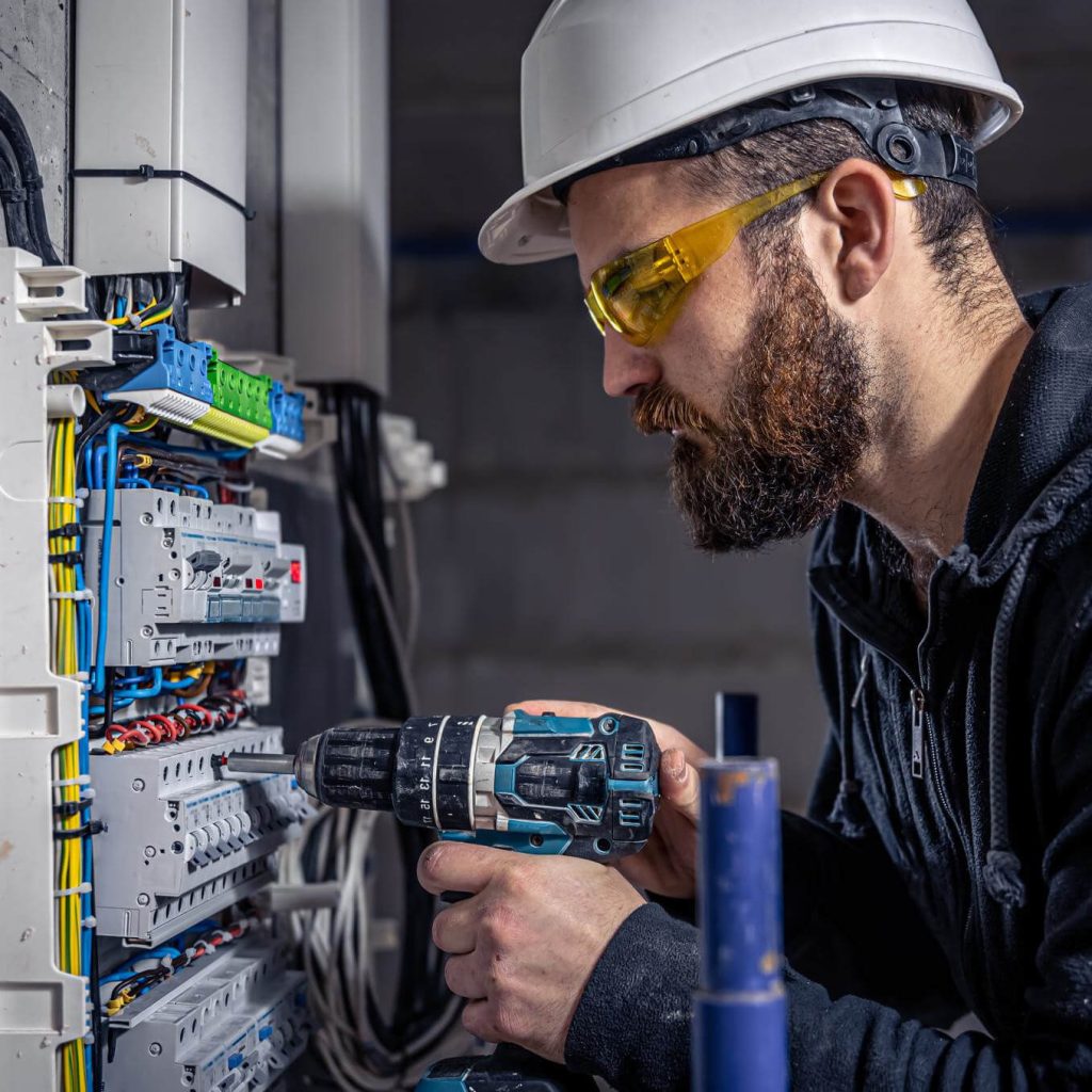 Electrician performing maintenance on a switchboard with proper safety procedures